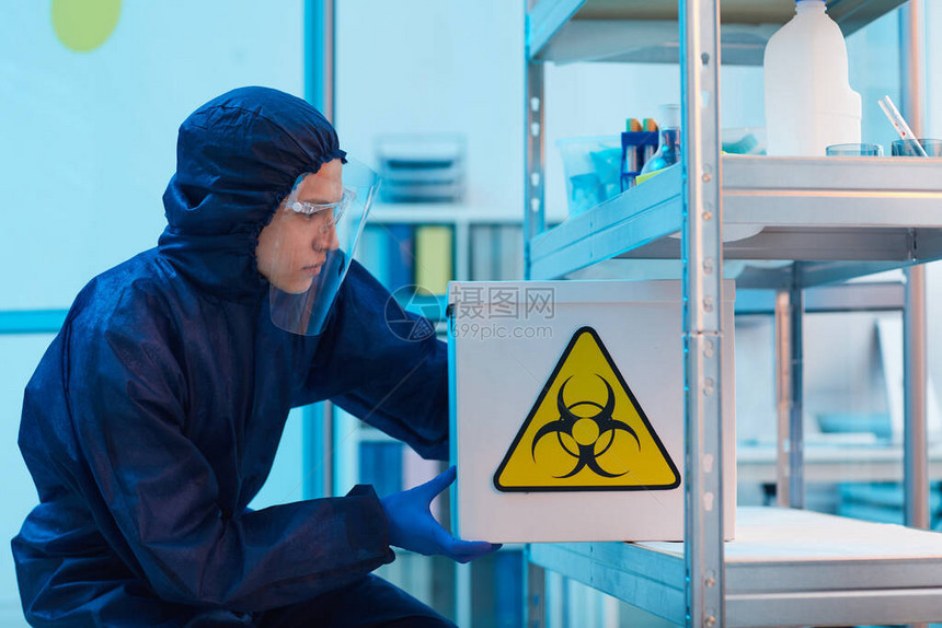男科学家在生物实验室复制空间进行研究时身着生物危害用具并装有危险标志的容器的图片