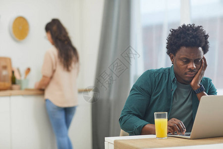 非洲严肃的男人端着一杯果汁坐在桌边图片