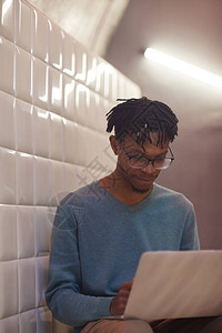 现代非裔美国人在用笔记本电脑坐在高墙楼梯上时使用图片