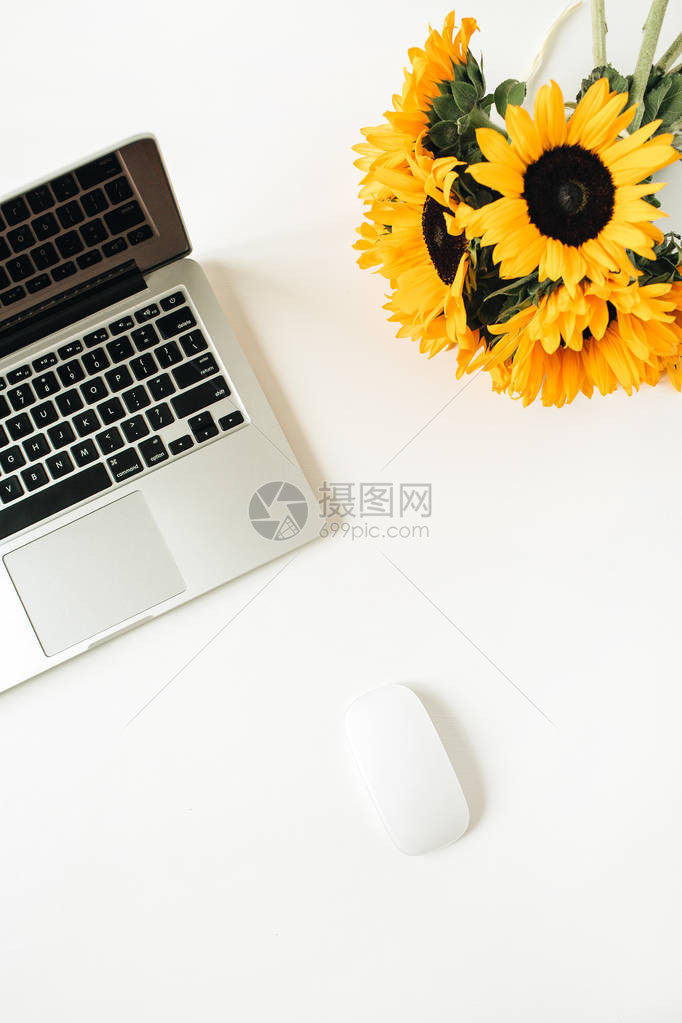 办公室办公桌工作空间有笔记本电脑白色背景的黄向日葵花束图片