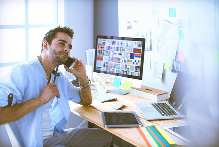 年轻设计师在线工作时坐在笔记本电脑和电脑前的图形背景图片