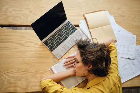 年轻疲累妇女最美的景色在办公用笔记本电脑和工作场所头下文背景图片