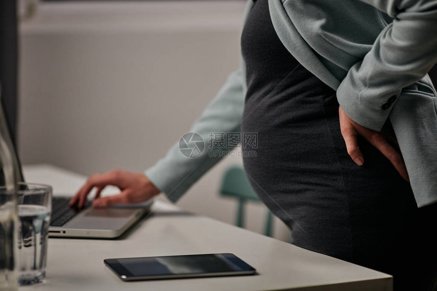 专心致志的怀孕女商人站在办公室使图片