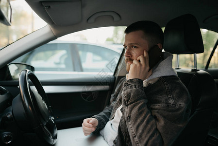 一个留着胡子的男人在舒适的车里用智能手机打电话图片