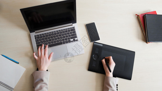 设计者用黑色屏幕和图形平板笔记本电脑工作的顶端视图图片