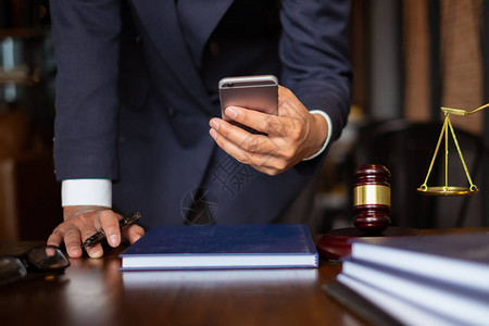 商业律师使用手机与办公室木桌上的黄铜秤联系客户法律法律服务建议咨图片
