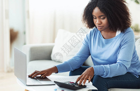 商业会计非洲女商人使用计算器和用笔记本电脑工图片
