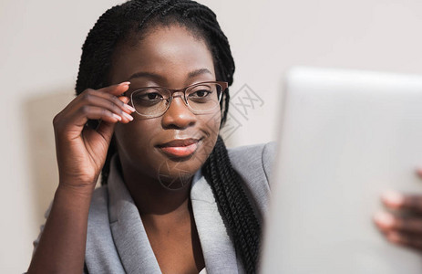具有自信的女企业家佩戴眼镜和使用数字板在办公室工作的肖像图片