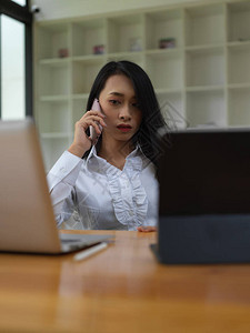 在办公室使用数字设备时女工在电话图片