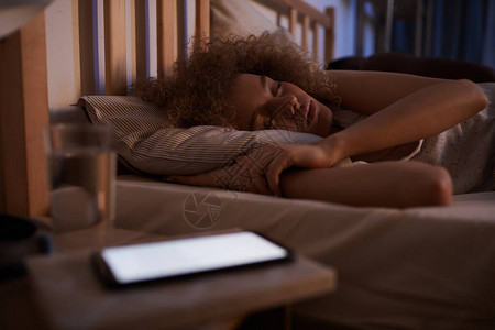 一头卷发的年轻女子晚上在床上平静地睡着图片