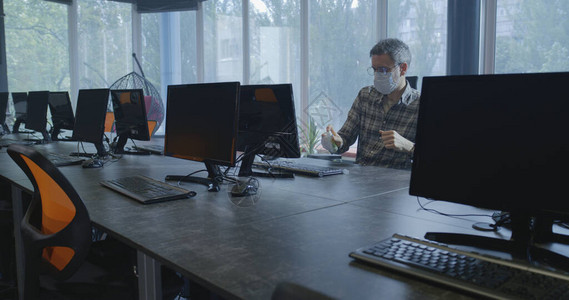 男子在工作场所的计算机上工作前用手消毒图片