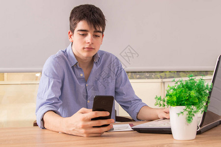 男青年少年或有手机和计算机的书桌学生图片