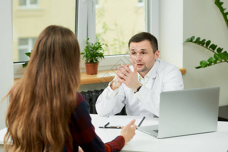 一位身穿白色实验室外套的白人医生坐在办公桌前图片