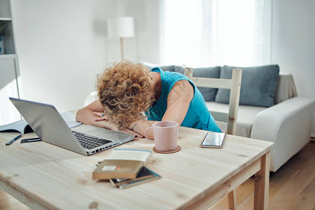 女人在远程自由职业工作时睡在家里的桌子上现代问题和在图片