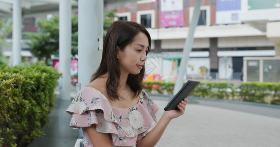 女在户外阅读电子图片