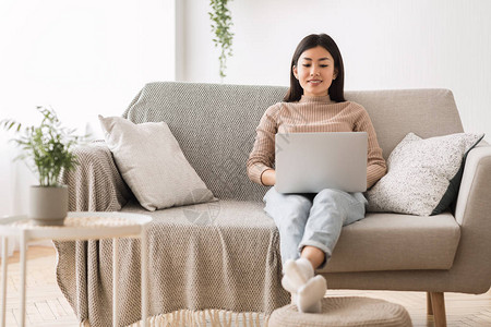 亚洲女孩在笔记本电脑上网在家沙发上休图片