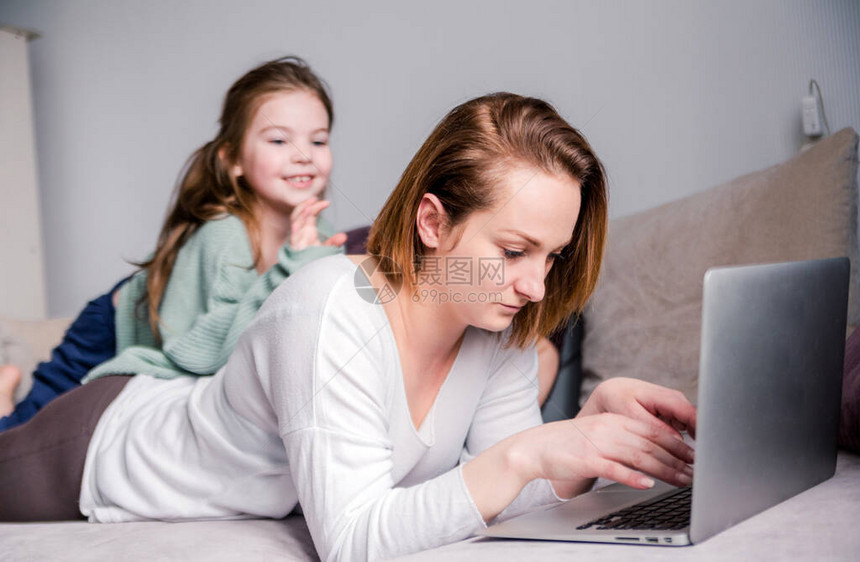 年轻女和两个孩子在家里用笔记本电脑工作孩子们想与母亲交流制造噪音和干扰工作冠状大流行期间的自我隔图片