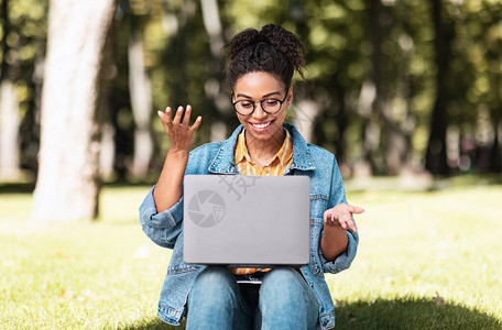 坐在绿色公园外面的黑人自由女郎使用笔记本电脑制作视频呼叫永远触图片