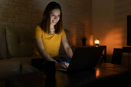 四十多岁的快乐女使用笔记本电脑在晚上与朋友聊天背景图片
