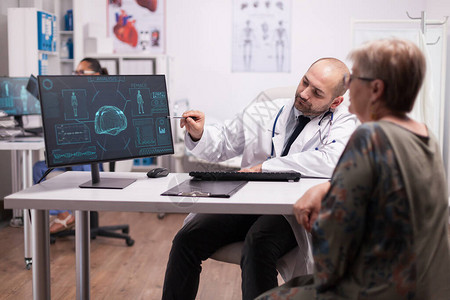 医生指向脑外科手术后看病期间高级病人在计算机上的Ct扫描图片
