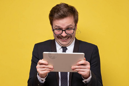 使用数码平板电脑握着眼镜的快乐男子惊讶地对社交媒体新闻感到震撼背景图片