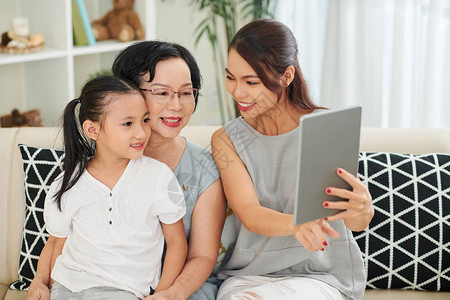 亚洲幸福家庭的母女和祖母一起坐在沙发上图片