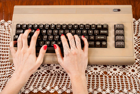 在旧电脑键盘上打字的女人图片