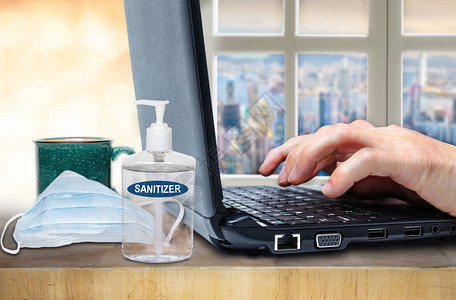 Covid19在电脑手提电脑键盘上用洗涤剂和桌上面罩显示手指之后图片
