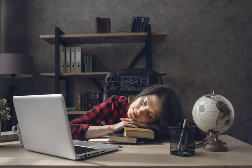 疲倦的女学生睡在她的书上图片