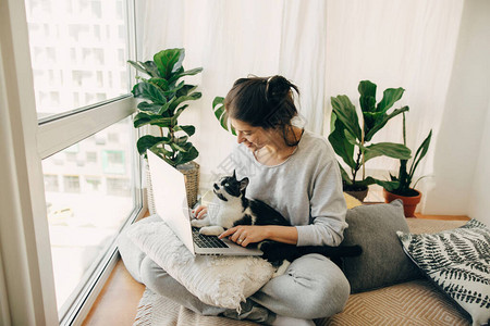 休闲女孩和她的猫一起在笔记本电脑上工作图片