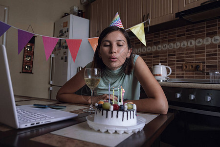女人吹灭生日蛋糕上的蜡烛并进行视频通话隔离期间在网上庆图片