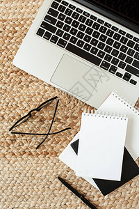 空白纸笔记本笔记本电脑眼镜柳条稻草背景上的钢笔图片