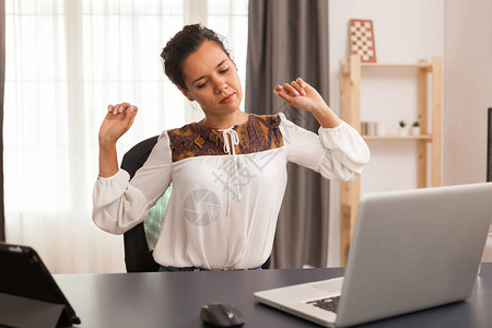 在家办公室使用笔记本电脑工作时背部疼痛的自由职业者图片