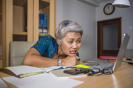 描绘了抑郁和过度劳累的中年有吸引力的亚洲女在笔记本电脑桌上工作压力大图片