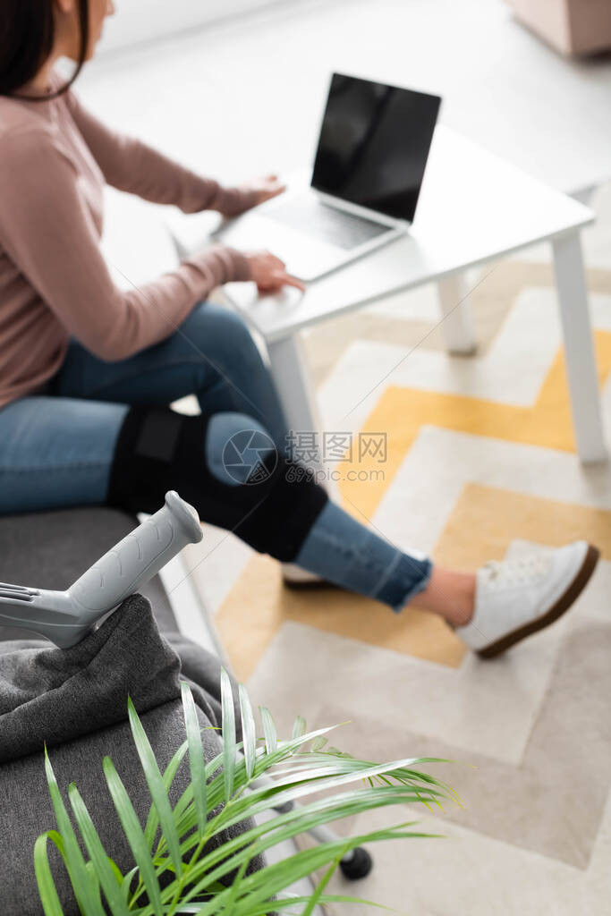以家庭笔记本电脑上与医生进行在线咨询的断腿妇女有图片
