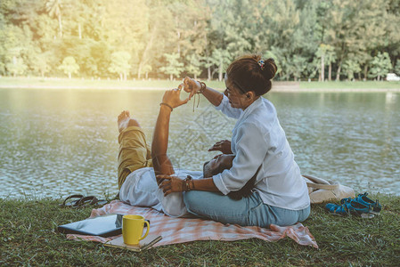 亚洲情侣恋人坐在公园里放松的河边图片