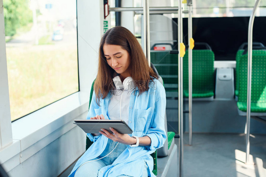美丽的女人在现代公共交通工具上阅读平板电脑或电子书年轻女学生乘坐现代电车前图片