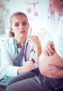 微笑的女医生在药片上向医院怀孕的年轻孕图片