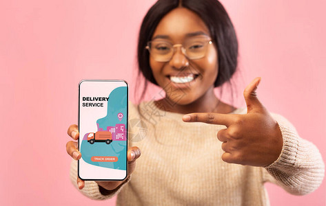 非洲女在移动屏幕粉红背景上展示手机图片