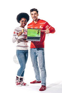 持有信用卡和有购物网站的笔记本电脑的多文化夫妇背景图片