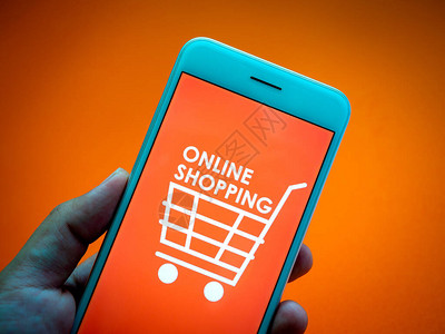 网上购物的概念橙色背景上的智能手机屏幕上橙色背景上的特写词在线购物图片