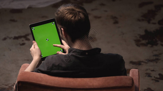 有棕色头发的黑衬衫男子在数字平板电脑绿色模拟屏幕上滑动图片