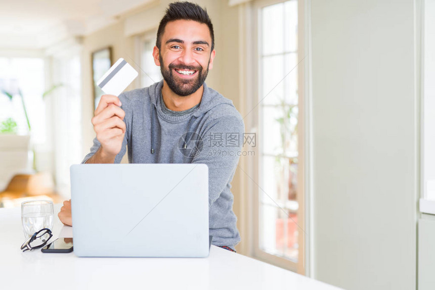 在网上用笔记本电脑购物时笑着以信用卡作为付款米多图片