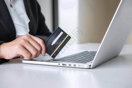 商务女消费者持有信用卡并在笔记本电脑上打字以进行在线购物和支付图片