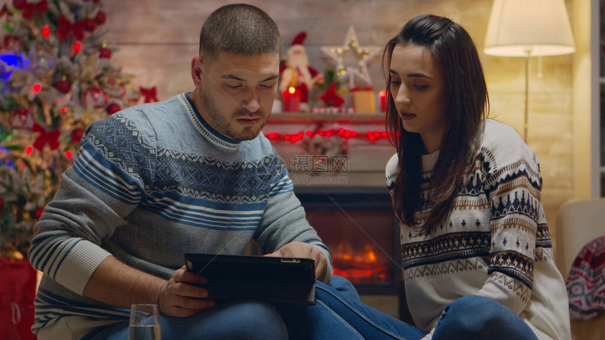 白种人夫妇在壁炉前用平板电脑网上购物图片