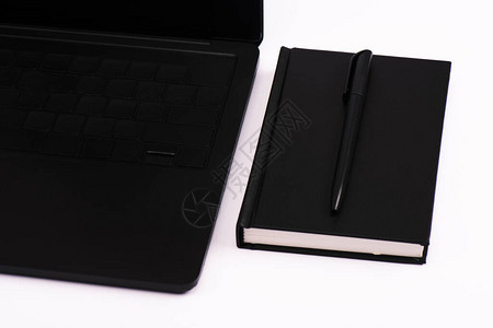 笔记本和笔靠近黑色笔记本电脑背景图片