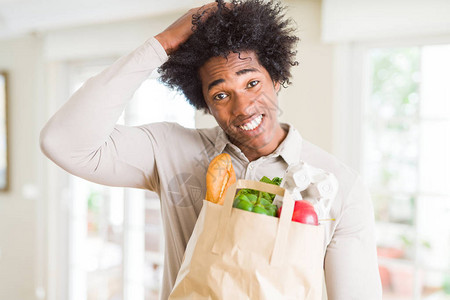 非洲裔美国人在家里拿着装新鲜蔬菜的杂货袋图片