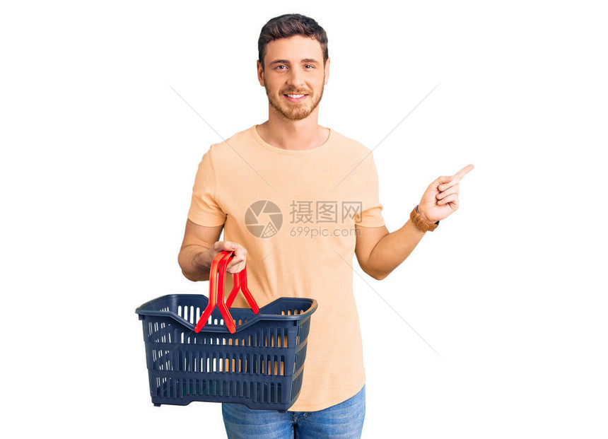 带着熊拿着超市购物篮的英俊年轻男子图片