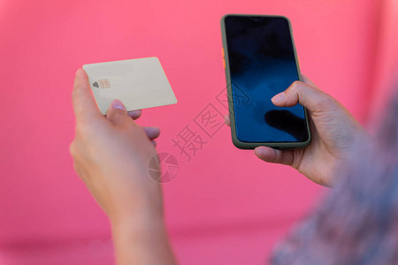 女人拿着信用卡在街上用手机付账图片