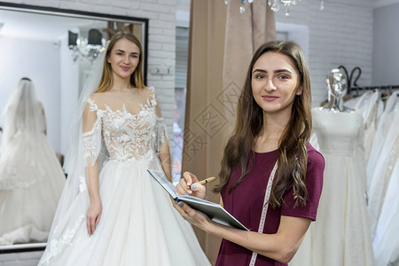 设计师用记事本和身后婚纱的新娘图片